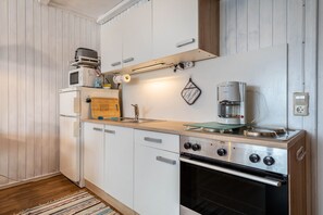 Een praktische keuken met witte kastjes, een ingebouwde oven, een koffiezetapparaat en een magnetron.