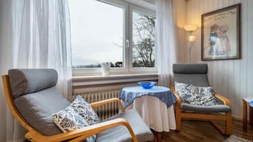 Ein gemütlicher Raum mit zwei grauen Sesseln, einem kleinen Tisch mit einer blauen Schale und einer Heizung.