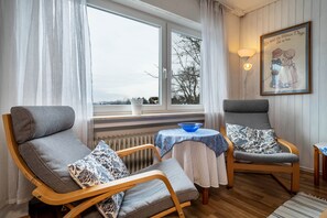 A cozy room with two grey armchairs, a small table with a blue bowl, and a radiator.