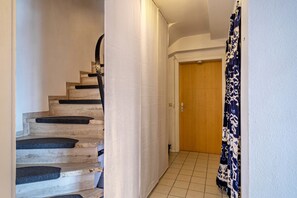 A staircase with a handrail, a door at the bottom, and a patterned curtain on the right.