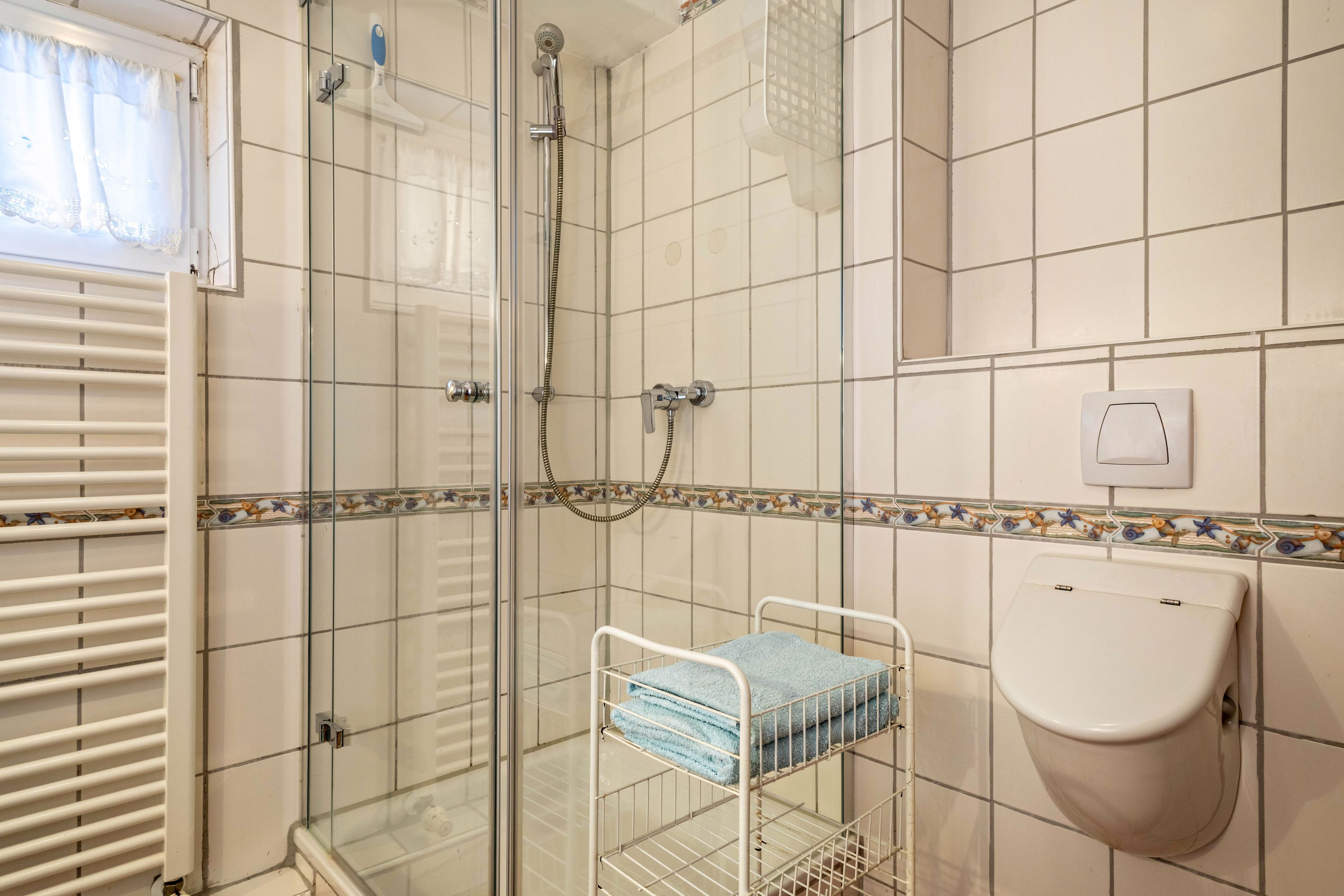 Une salle de bain avec une douche à parois de verre, un lavabo blanc et un porte-serviettes avec des serviettes pliées.