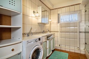 Een kleine badkamer met een wasmachine, een wastafel en een spiegel.