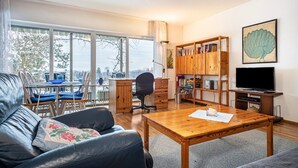 A living room with a sofa, a coffee table, a TV, a bookshelf, and a dining area with chairs and a table. - Holiday Apartment "Adlerhorst" with Mountain View, Private Terrace & Wi-Fi (Wangen)