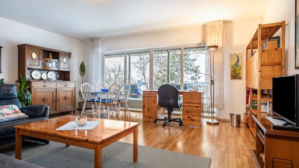 A living room with a wooden coffee table, a sofa, a desk with a chair, and a television. - Holiday Apartment "Adlerhorst" with Mountain View, Private Terrace & Wi-Fi (Wangen)