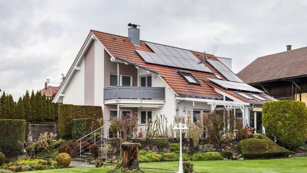 A two-story house with a red-tiled roof, solar panels, a balcony, and a well-maintained garden. - Holiday Apartment in the Countryside with Mountain View, Balcony and Wi-Fi (Wolpertswende)