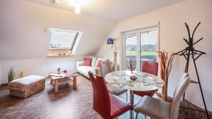 A modern living room with a sofa, a round table, and a dining area. - Holiday Apartment in the Countryside with Mountain View, Balcony and Wi-Fi (Wolpertswende)