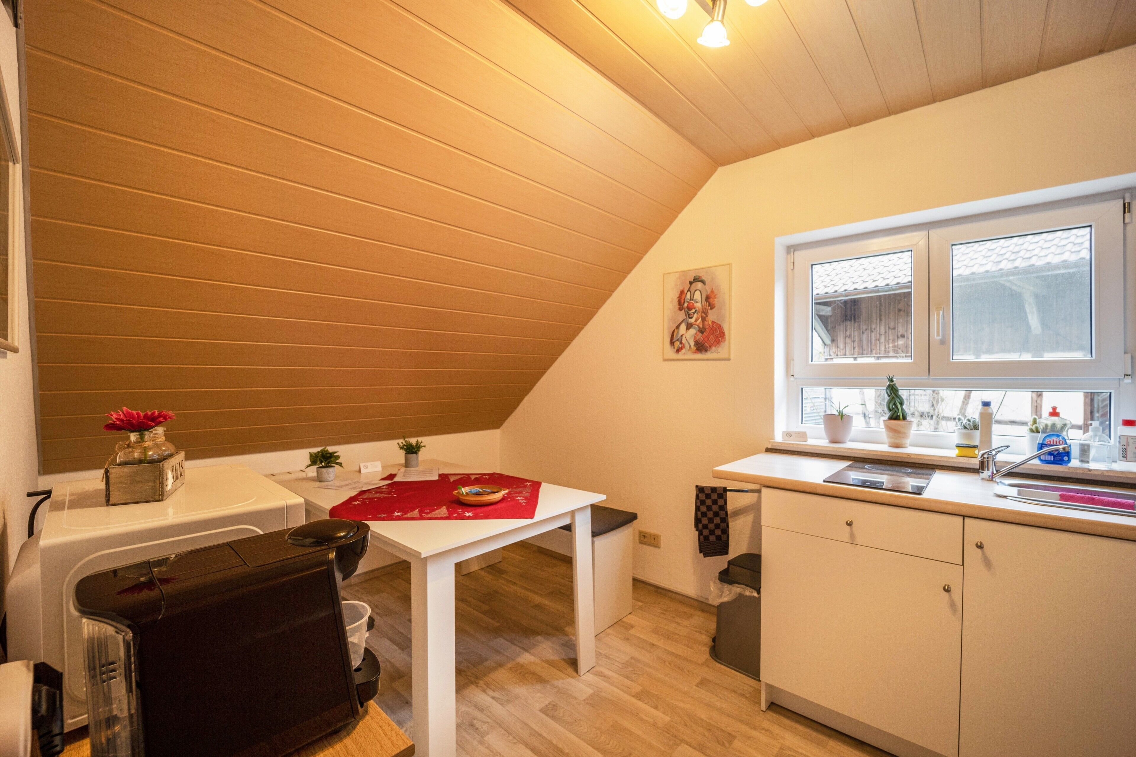A kitchen with a white table, a window with a view, and a ceiling with wooden beams.