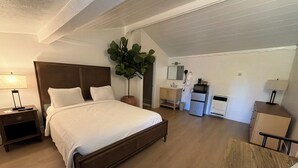 Una camera da letto con un letto, un comodino, una lampada e una pianta in vaso.