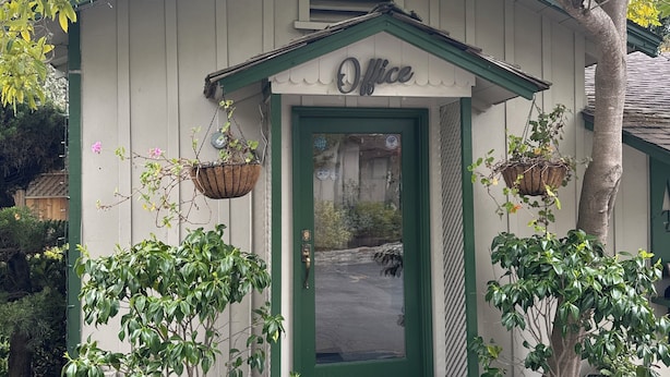 Un piccolo edificio con una porta verde e la scritta 'Office' sopra.