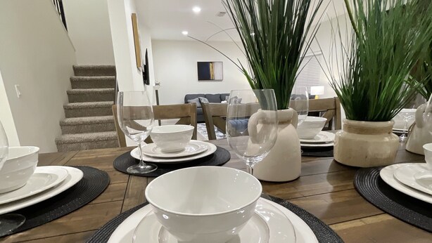 A dining table set with white plates and bowls, surrounded by black placemats.