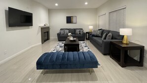 A modern living room with a flat-screen TV, two sofas, a coffee table, and a fireplace.