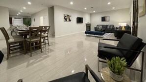 A spacious living room with a dining area, a fireplace, and a television mounted on the wall.