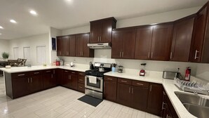 A modern kitchen with dark wooden cabinets, stainless steel appliances, and a light-colored countertop.
