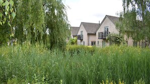A residential area with houses, dense greenery, and tall grass. - Bridge House (Cirencester)