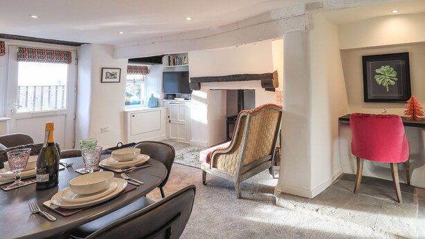 A dining area with a table set for four, a sofa, and a kitchen in the background. - Violet Cottage (Ambleside)