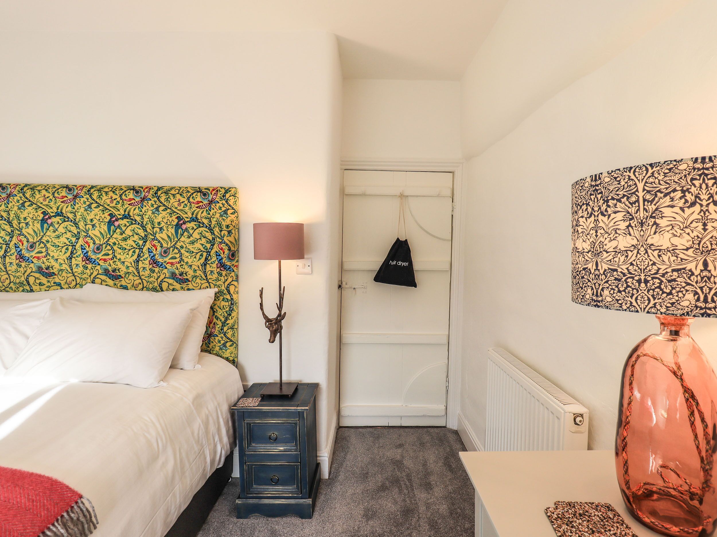 A bedroom with a bed, bedside lamp, nightstand, and a dresser.