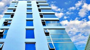Un immeuble de grande hauteur, doté de nombreuses fenêtres, se dressant sous un ciel dégagé parsemé de nuages.