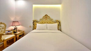 Une chambre d’hôtel avec un grand lit, une table de chevet avec une lampe et une chaise.