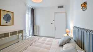 Een slaapkamer met een bed, nachtkastje, lamp en een decoratie aan de muur.
