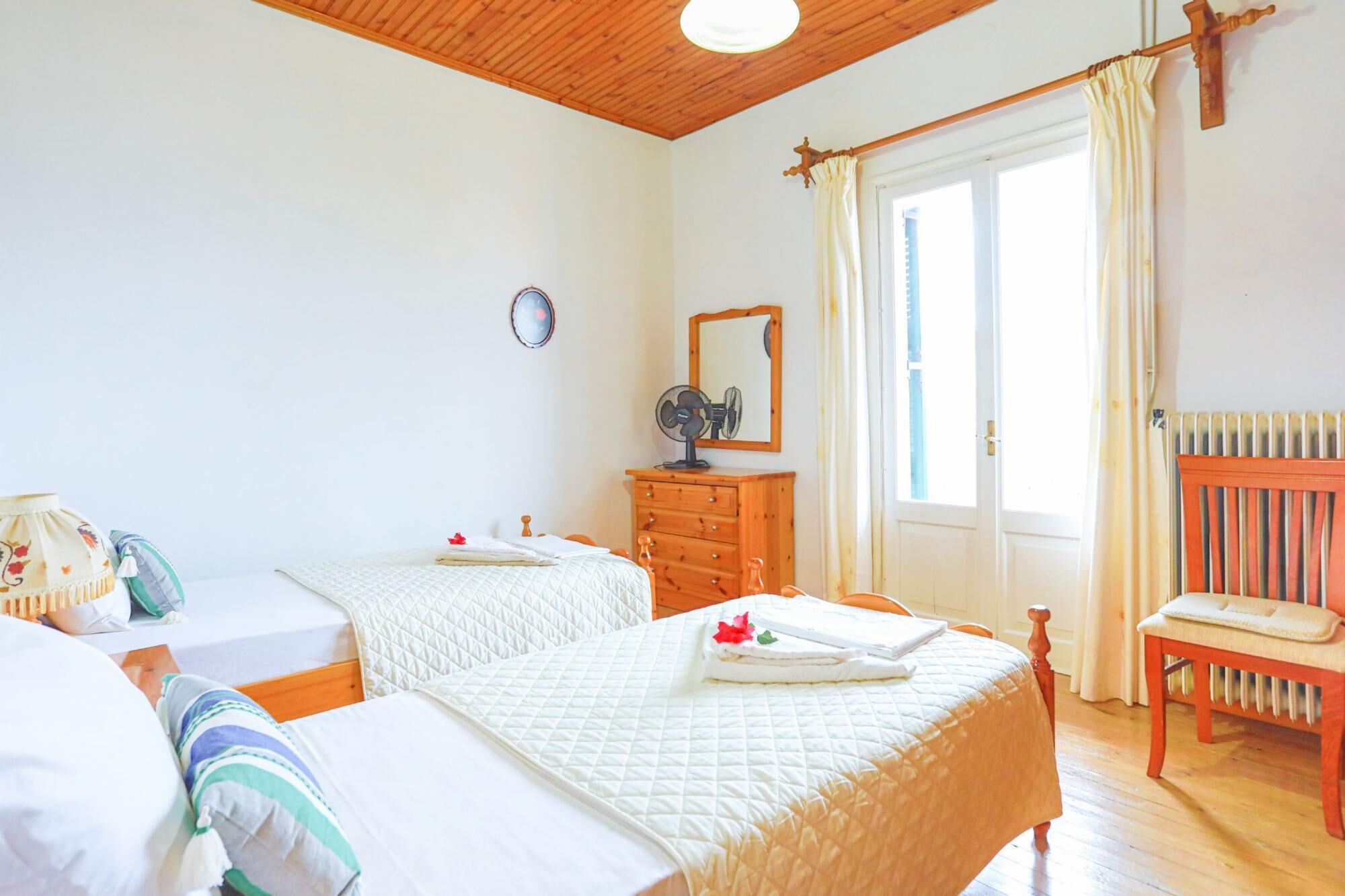 Een slaapkamer met twee bedden, een kapstok, een stoel, een spiegel en een radiator.