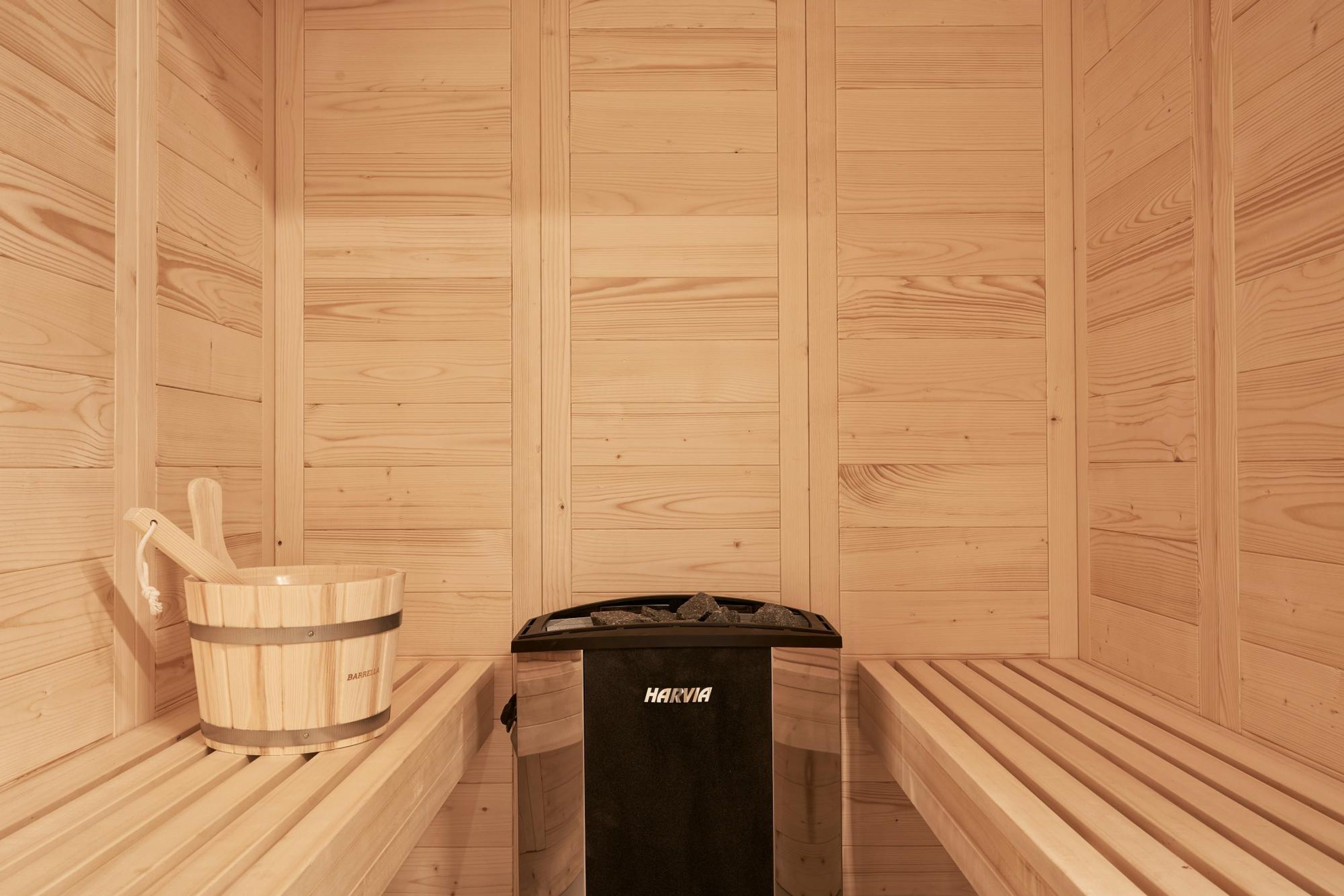 A wooden sauna with benches and a wooden bucket.