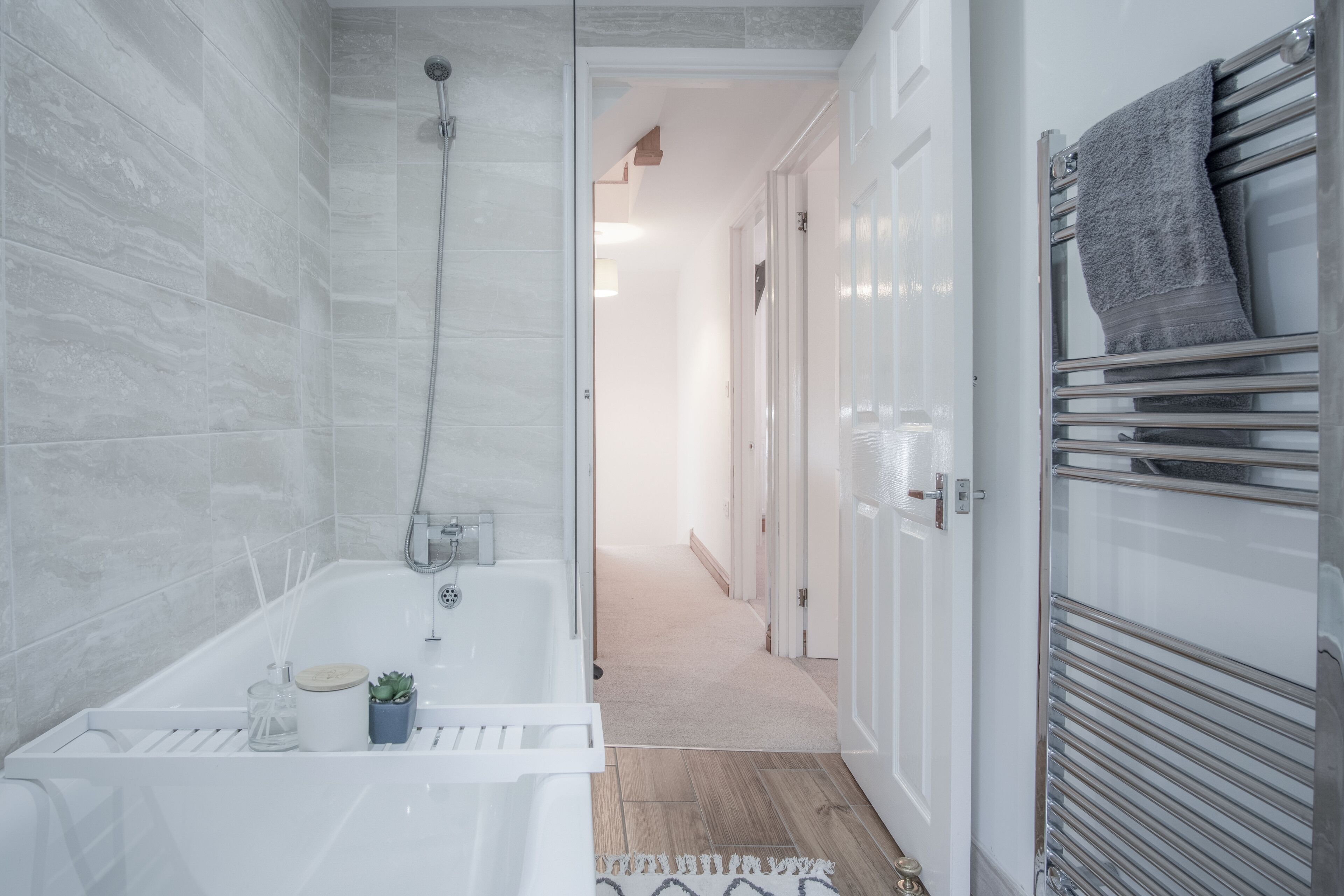 A modern bathroom with a bathtub, shower, and a towel rack.