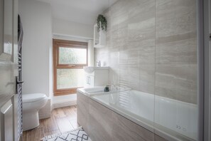 Ein modernes Badezimmer mit Badewanne, Toilette und Waschbecken.