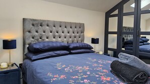 A bedroom with a tufted headboard, a floral bedspread, and a skylight above the bed. - Luxury Small Cozy House With Lake View (Doncaster)