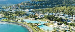 A resort with multiple swimming pools, a beachfront, and a mountainous backdrop. - Tropical Marina views couples getaway (Airlie Beach)