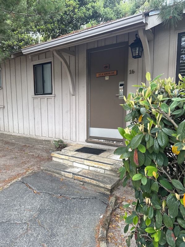 A small, single-story building with a wooden exterior, a door labeled "1st & Guadalupe," and a small window.