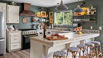 A kitchen with a central island, bar stools, a stove, and a window with a view.