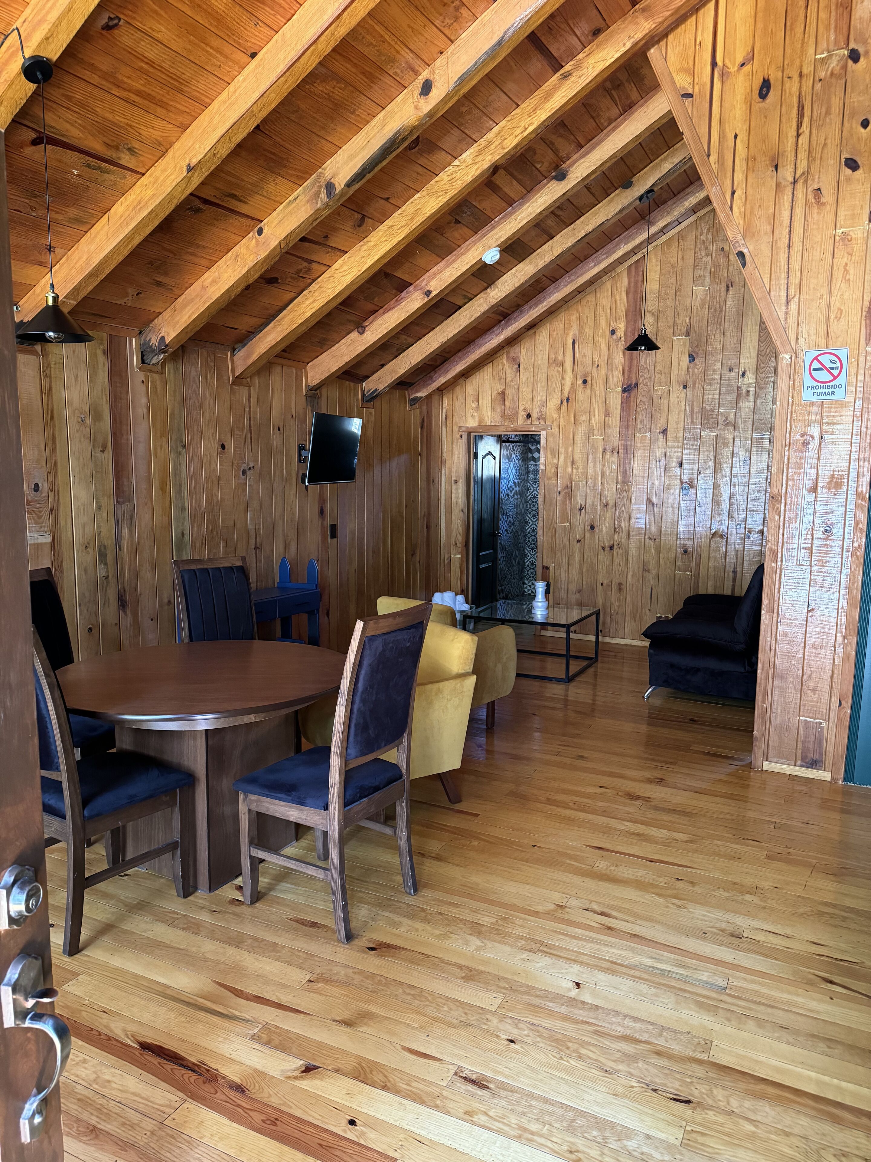 A wooden interior with a dining area, a sofa, and a television.