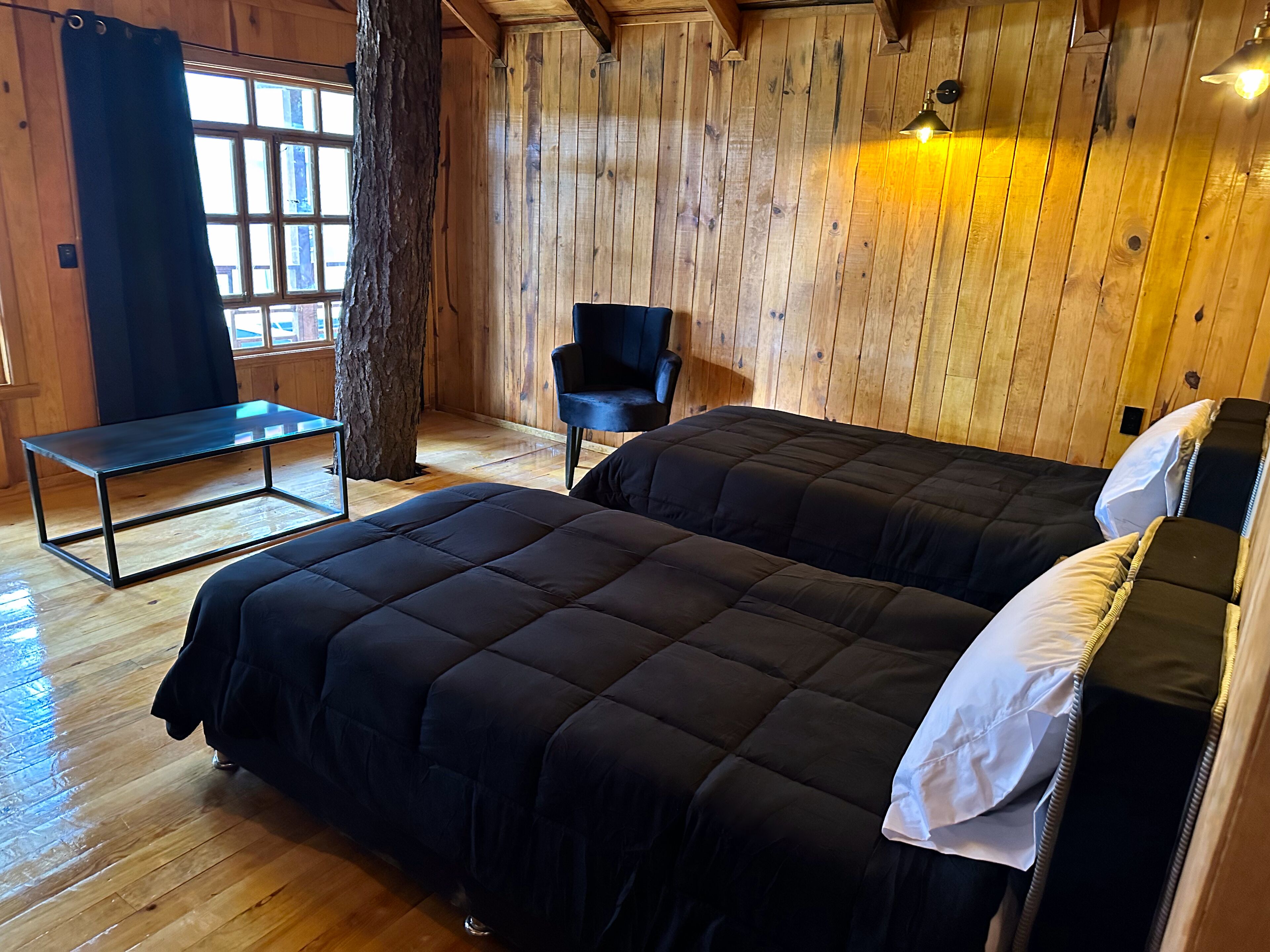 A wooden room with two beds, a bench, and a chair.