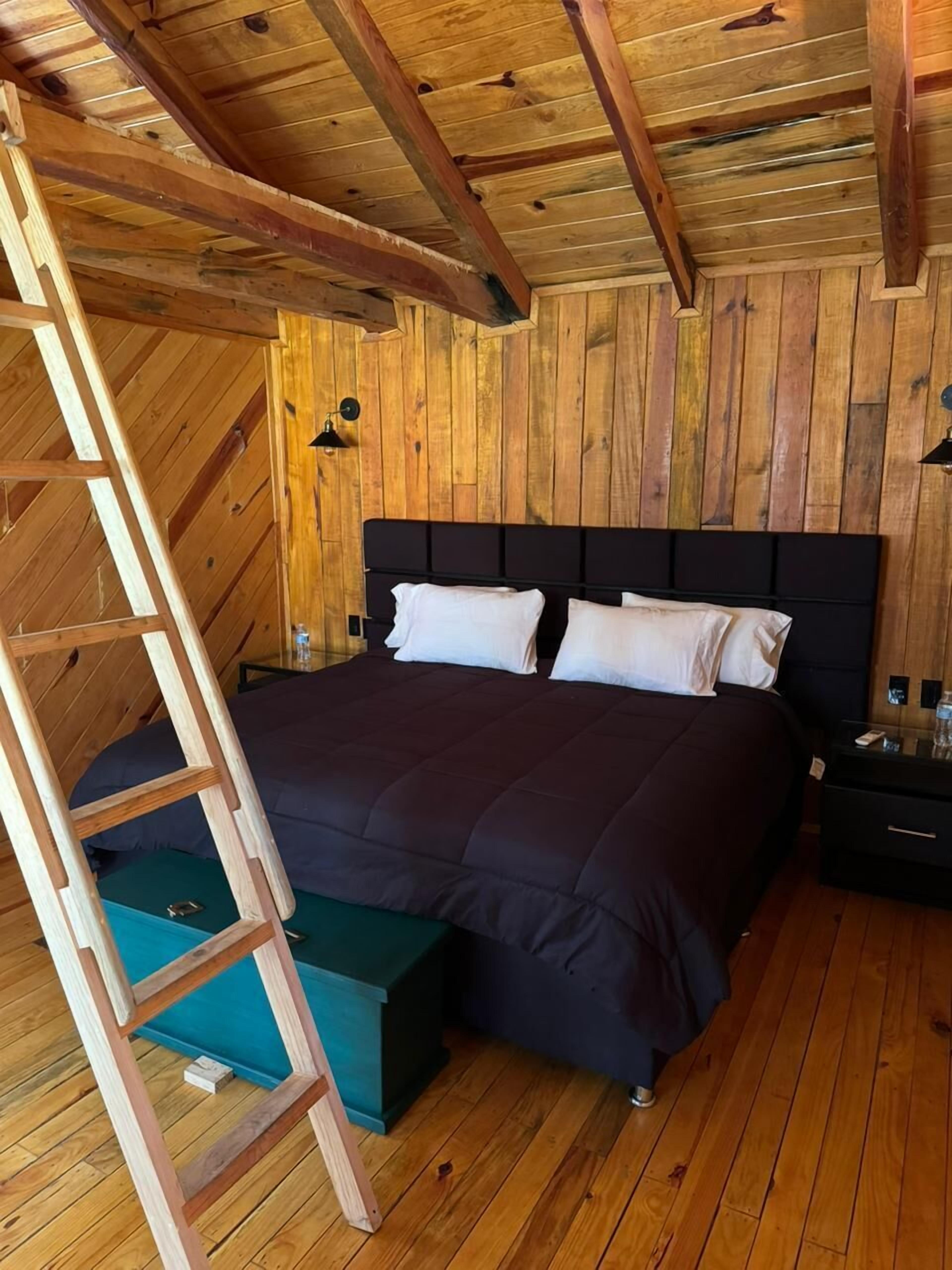 Un dormitorio con paneles de madera, una cama, una escalera y una mesita de noche.