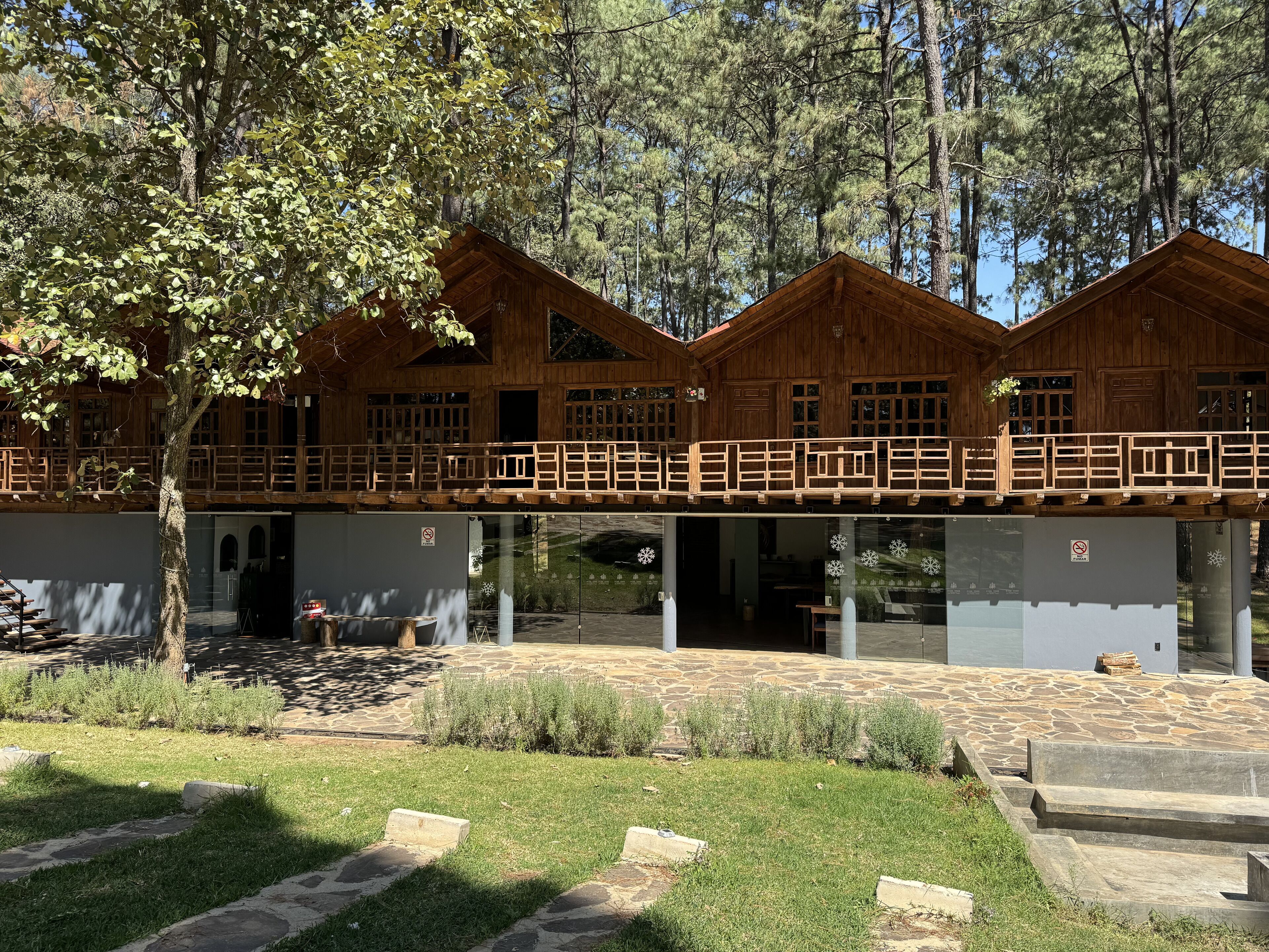A wooden cabin with a balcony, stone steps, and a grassy area.