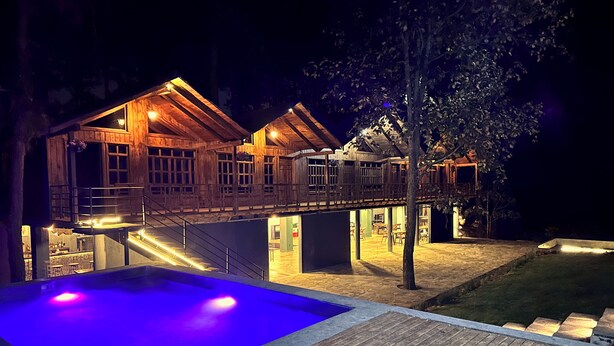 Een houten vakantiehuis met een zwembad en een overdekt terras.