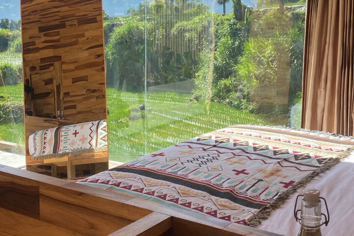 A wooden cabin room with a large window overlooking a lush landscape.