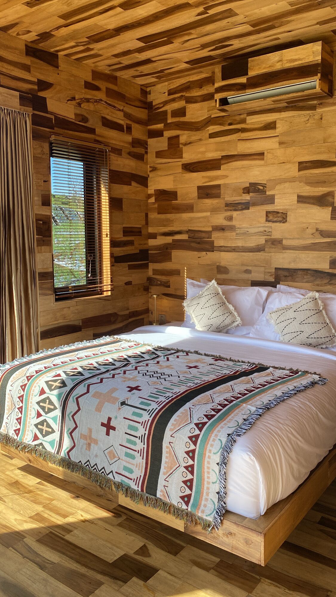 A wooden room with a bed, a window, and a curtain.