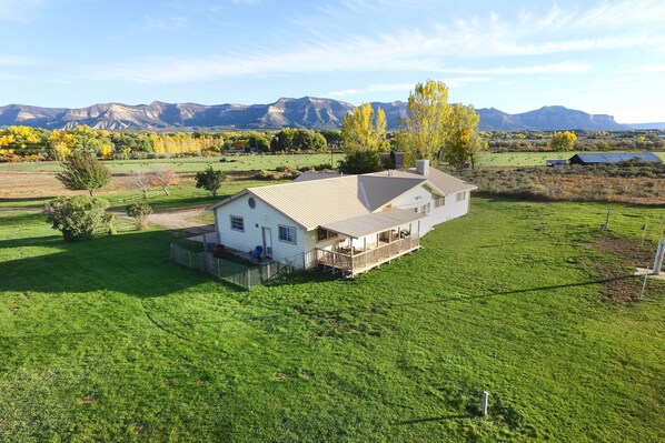A single-story house with a fenced yard and a large mountain backdrop. - Cortez Retreat w/ Office & Stunning Mtn Views (Cortez)