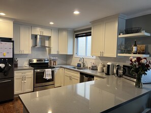 Una cocina moderna con armarios blancos, electrodomésticos de acero inoxidable y encimera de granito.
