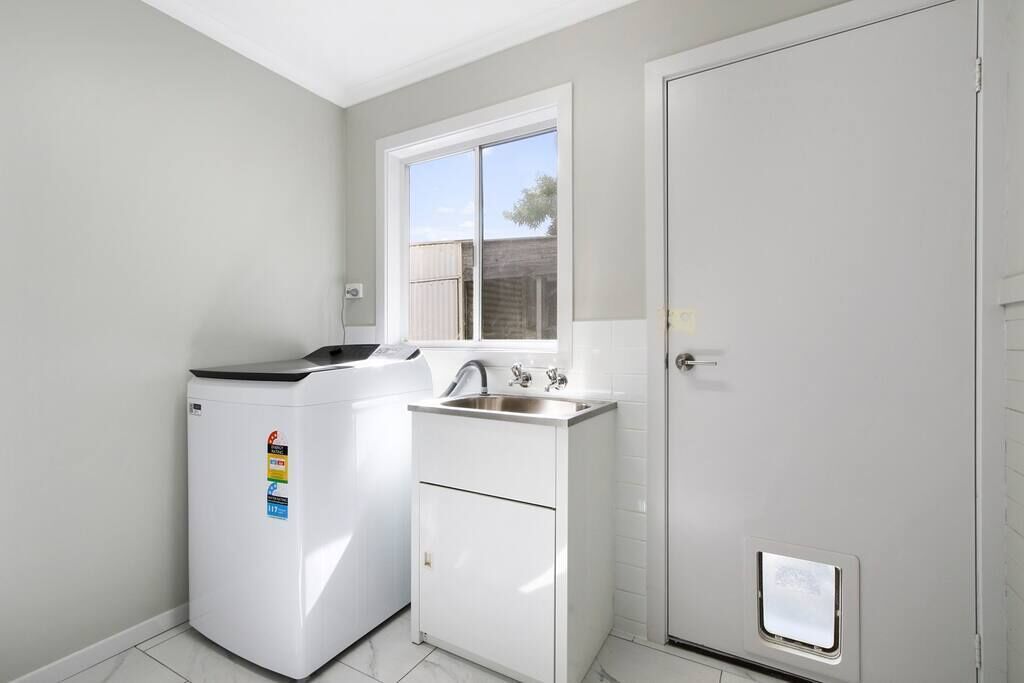 A compact kitchen with a washing machine, a sink, and a door.