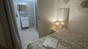 Une chambre à coucher comprenant un lit, des lampes de chevet, un miroir et une porte donnant sur une salle de bain.