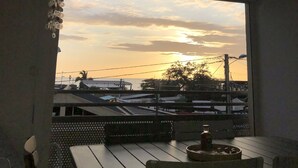 Un balcon avec vue sur le coucher de soleil, une table et des chaises.