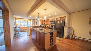 A spacious kitchen with wooden cabinets, a large island, and a built-in refrigerator. - Pines 2116 (Keystone)