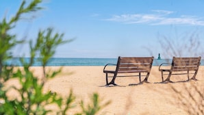Two wooden benches on a sandy beach with a clear sky and a distant lighthouse. - Sokcho Bird Island Pension (Sokcho)