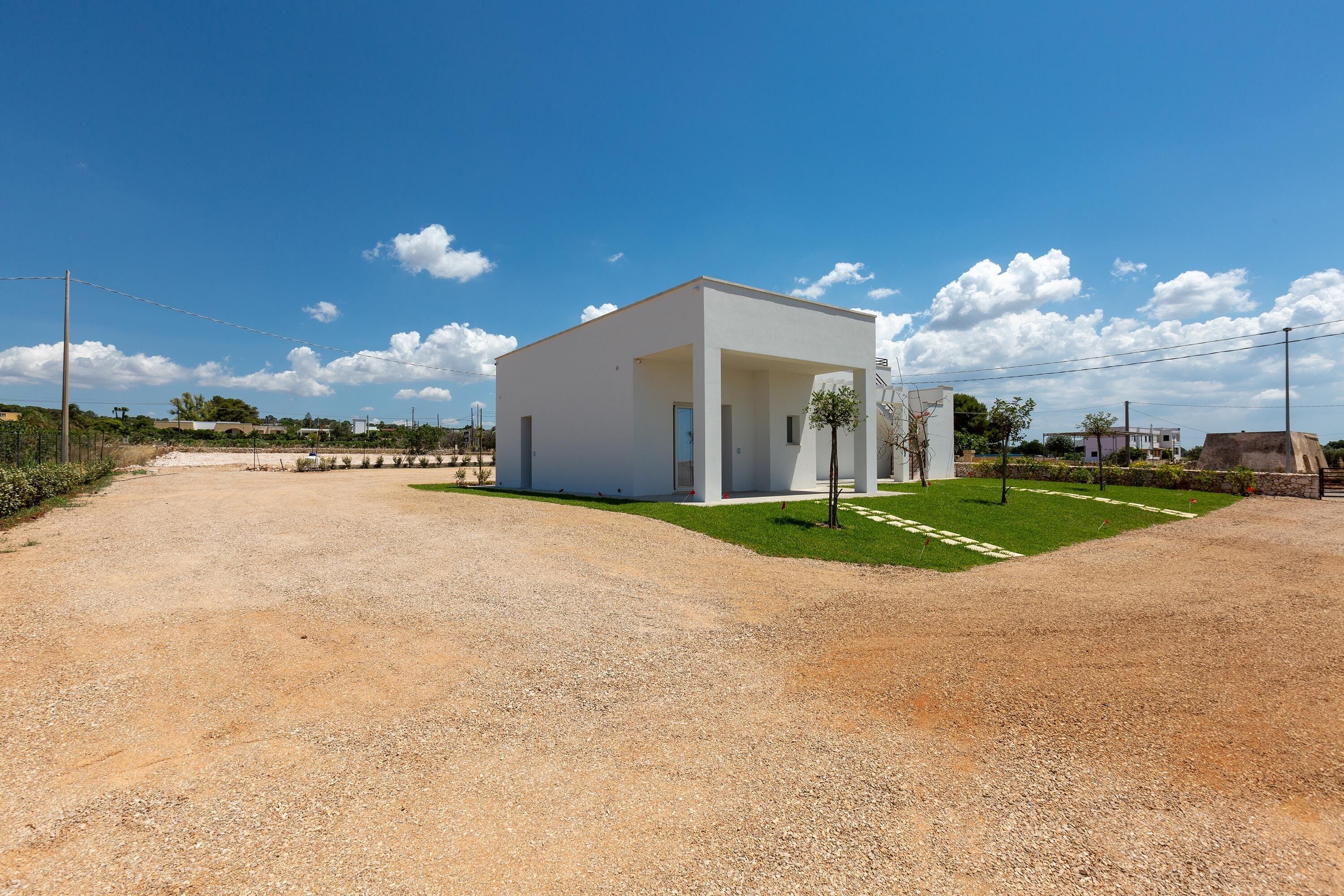 A modern, single-story building with a flat roof, a gravel driveway, and a well-maintained lawn.