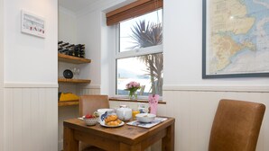 A breakfast table with a map, a wine rack, and a chair. - Oystercatcher House (St Ives)