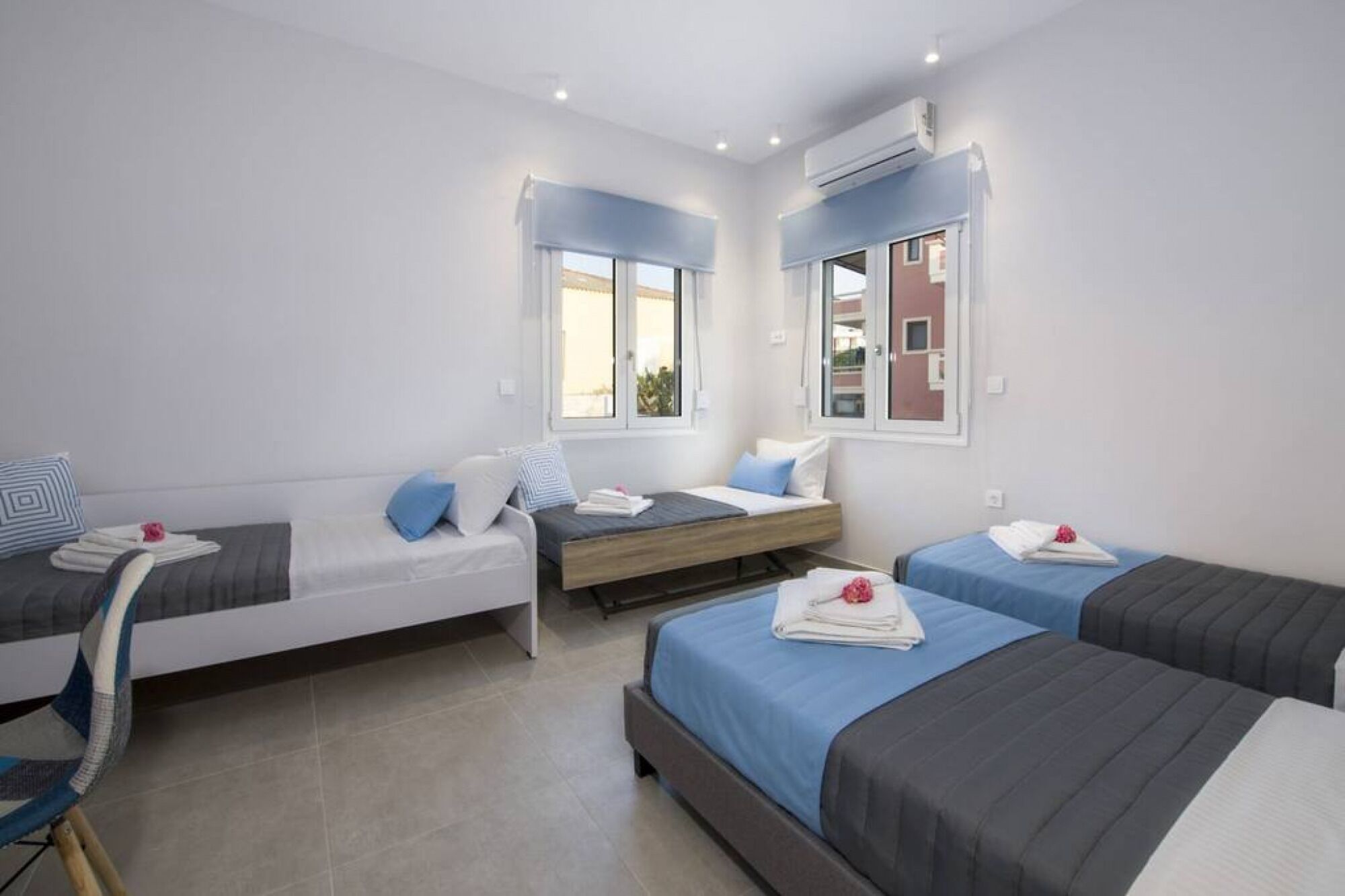 Quarto de hotel com três camas, um sofá e uma cadeira.