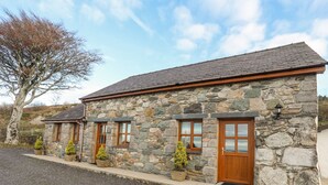 A stone building with a tiled roof, wooden doors, and windows. - Beech Tree Cottage (Caernarfon)