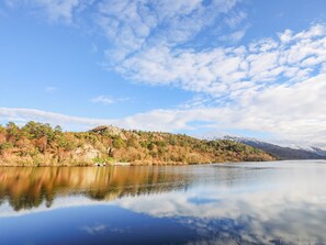Ein ruhiger See mit einem Bergpanorama im Hintergrund und einem klaren Himmel.